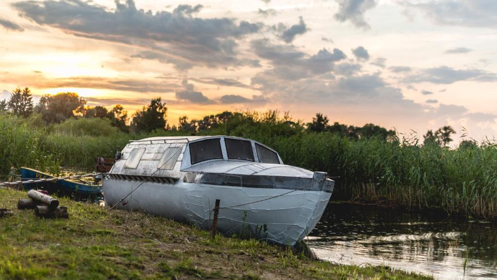 a boat sitting on the side of a river at Lake Peipsi boathouses in Varnja