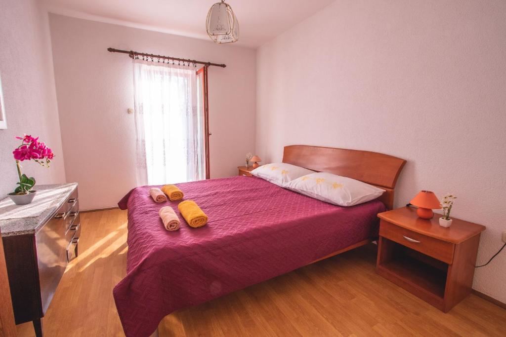 Dormitorio con cama con colcha púrpura y objetos amarillos. en Kristian Apartments, en Rovinj