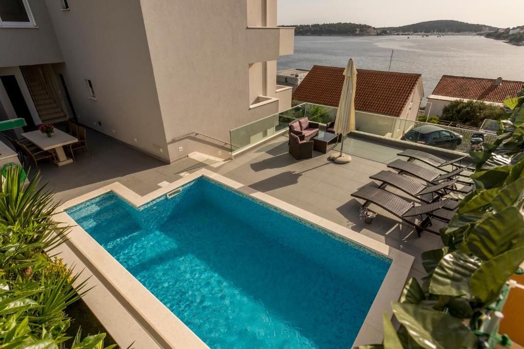 a swimming pool with chairs next to a house at Villa Rogoznica in Rogoznica