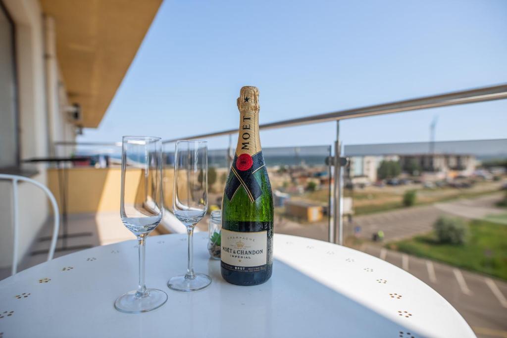 una bottiglia di vino seduta su un tavolo con due bicchieri da vino di Summerland Happy Blue Apartments a Mamaia