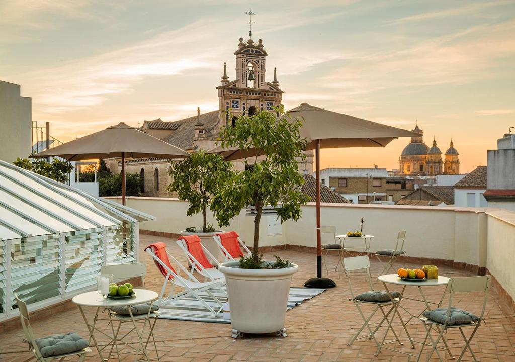 een dakterras met tafels en stoelen en een klokkentoren bij Santa Paula Pool & Luxury in Sevilla