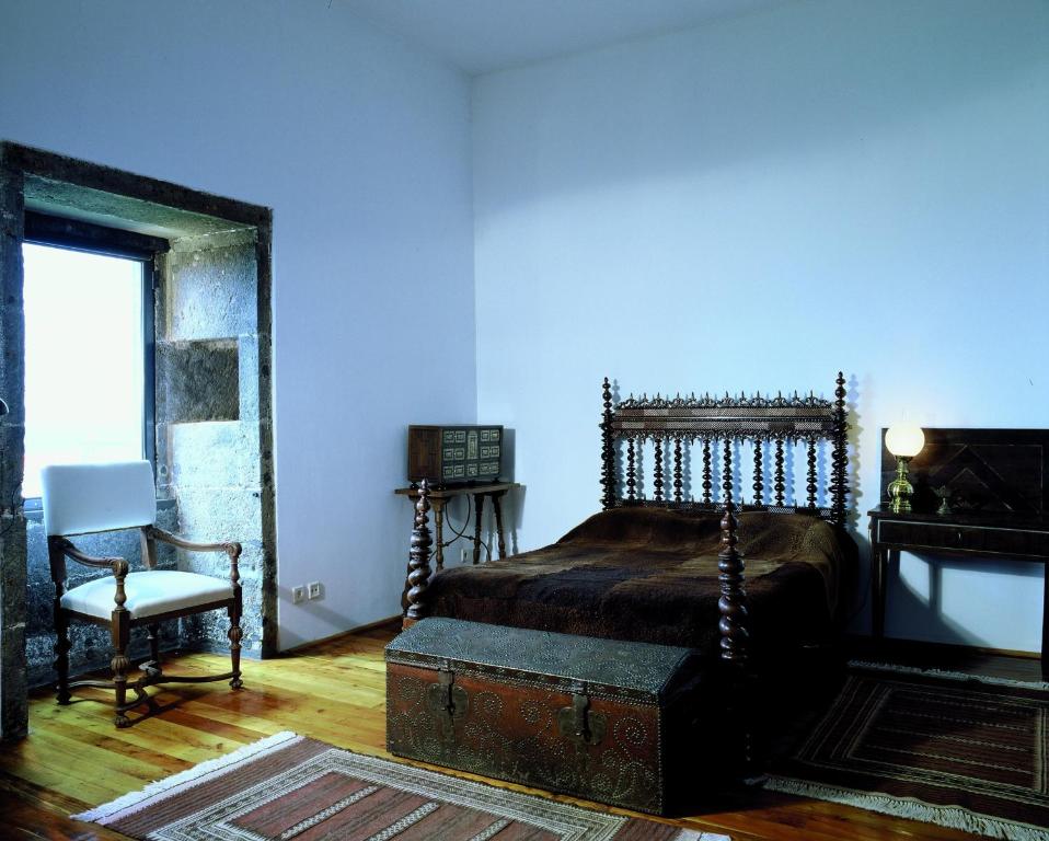 a bedroom with a bed and a chair and a window at Convento de São Francisco in Vila Franca do Campo