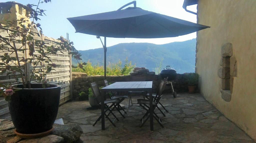 eine Terrasse mit einem Sonnenschirm, einem Tisch und Stühlen in der Unterkunft Gîte Laboule pour 4 personnes in Laboule