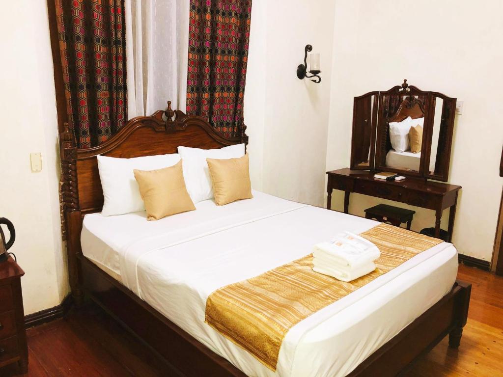 1 dormitorio con 1 cama con cabecero de madera y espejo en My Vigan Home Hotel en Vigan