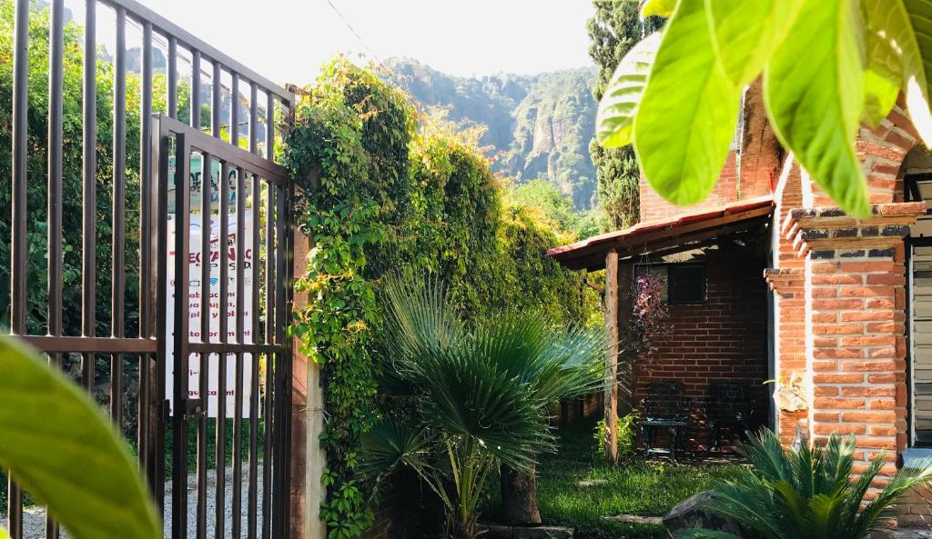 un portail en fer avec un bâtiment en briques et des plantes dans l'établissement Posada Teopanco, à Tepoztlán
