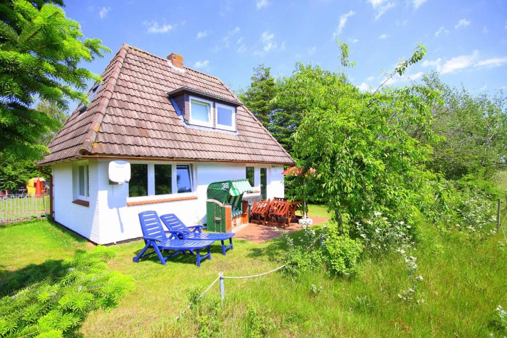 a small white house with a picnic table in the yard at Das kleine Haus - Reetdachhaus Petersen in Nebel