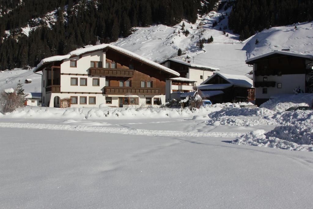 pokryty śniegiem budynek przed górą w obiekcie Haus Astoria w mieście St. Leonhard im Pitztal