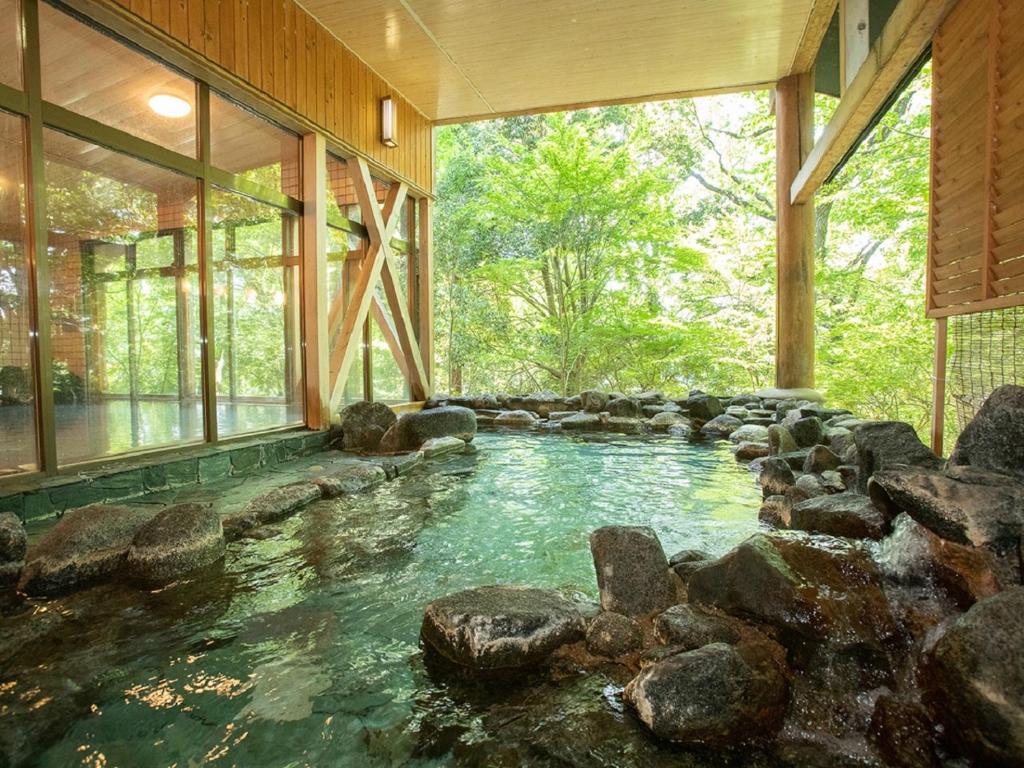 a pool in a house with rocks in the water at Hotel Okukujikan in Daigo