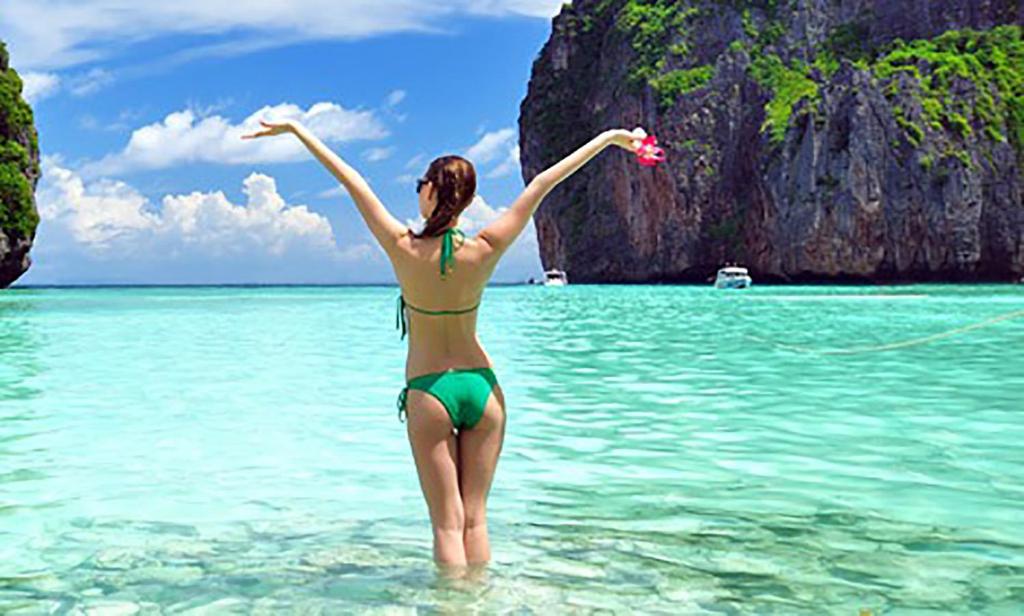una mujer parada en el agua en el océano en The Shades Hotel 50 meter Beach Front, en Patong Beach