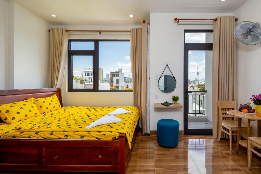 a bedroom with a yellow bed and a table and chairs at Loving Homestay & Apartment Da Nang in Danang