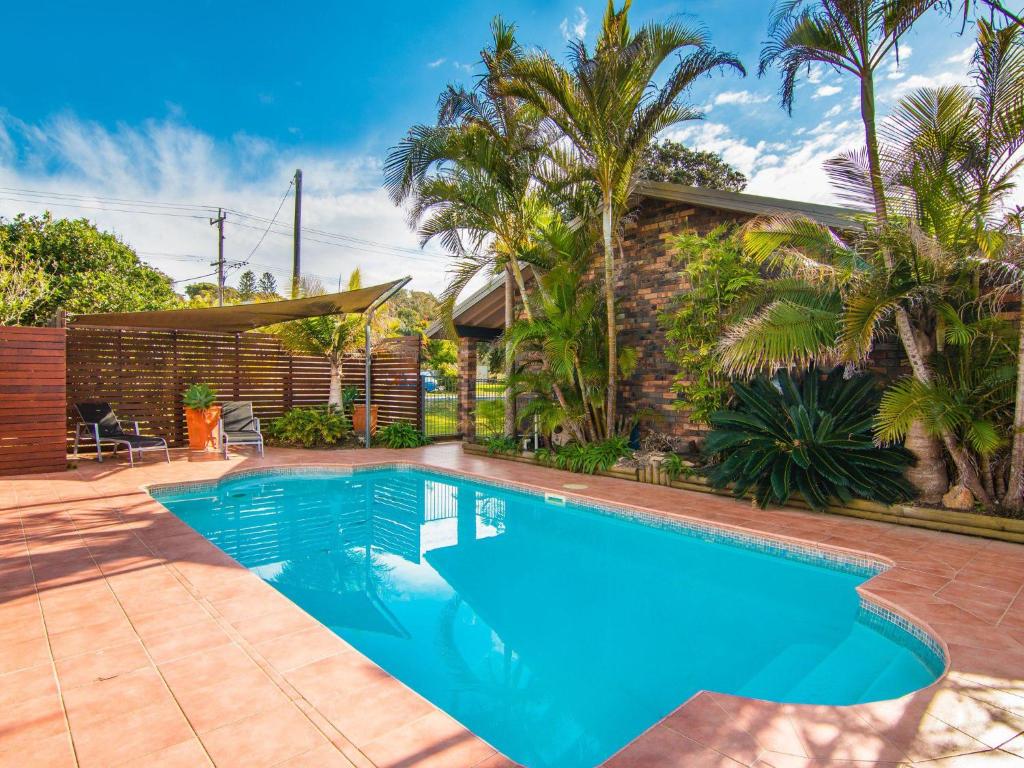 een zwembad in de achtertuin van een huis met palmbomen bij 40 Underwood Road in Forster
