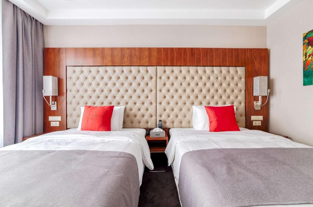 圣罗伯Hawthorn Extended Stay by Wyndham Saint Robert的两张位于酒店客房的床铺,配有红色枕头