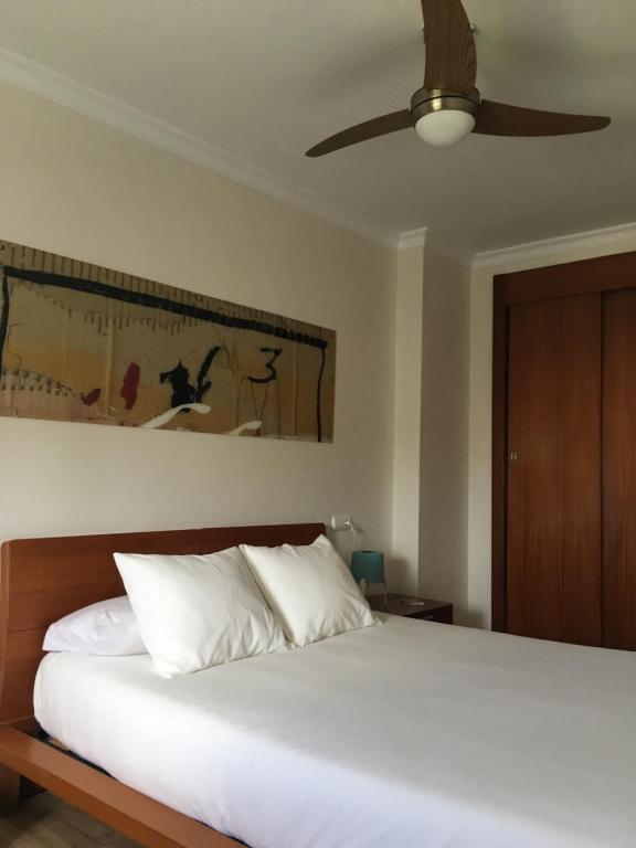 um quarto com uma cama branca e uma ventoinha de tecto em Albaida Estepona em Estepona
