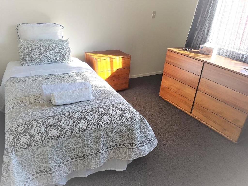 um quarto com uma cama e uma cómoda em madeira em Sylvia Park House em Auckland