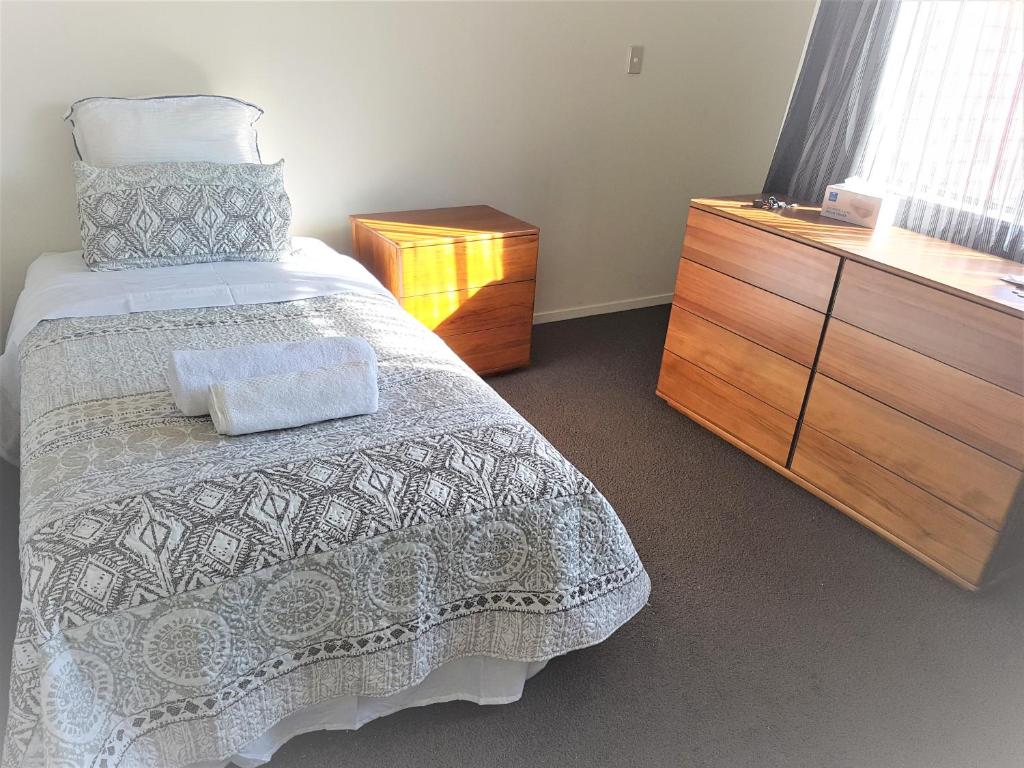 a bedroom with a bed and a wooden dresser at Sylvia Park House in Auckland