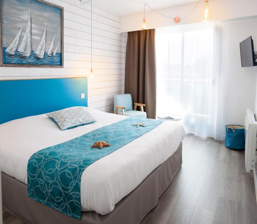 une chambre d'hôtel avec un grand lit avec une tête de lit bleue dans l'établissement Hôtel La Côte Océane, à Saint-Jean-de-Monts