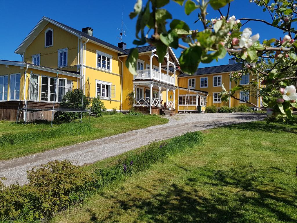 a large yellow house with a dirt road at Nygården B&B Hälsingegård in Harmånger