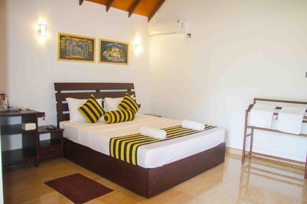 a bedroom with a bed with yellow and black pillows at Sigiriya Nature Resort in Sigiriya