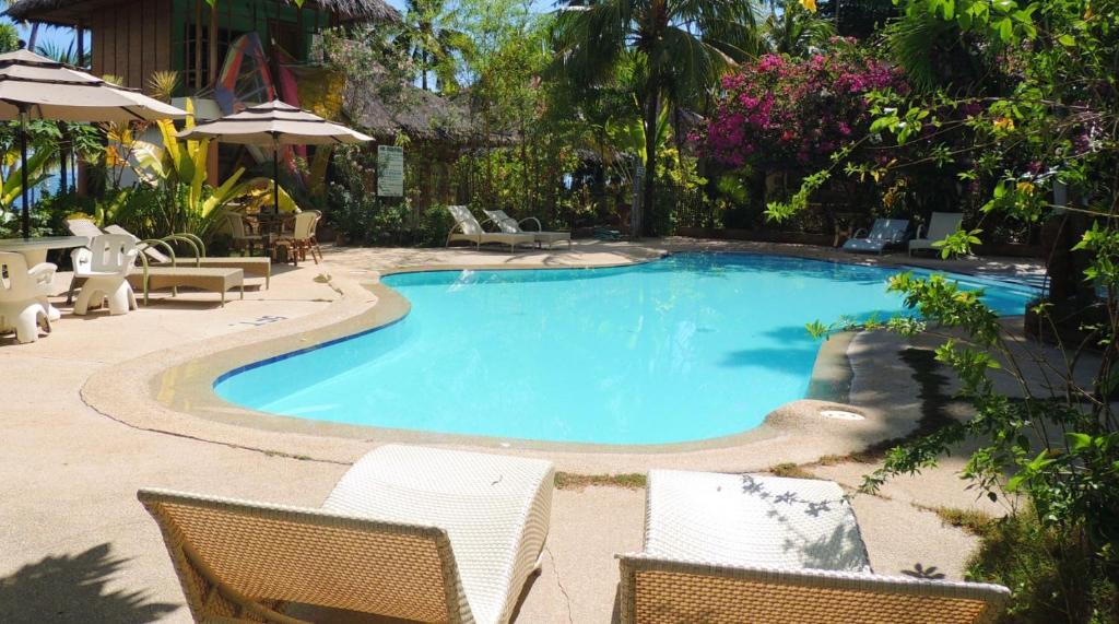 a swimming pool with two chairs and a table at Coral Cay Resort, Inc. in Siquijor