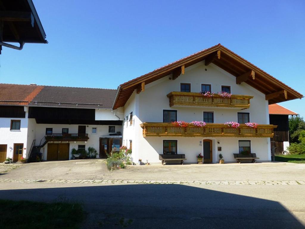 ein großes weißes Gebäude mit einem Balkon mit Blumen darauf in der Unterkunft Ferienwohnung Bösch in Taching am See