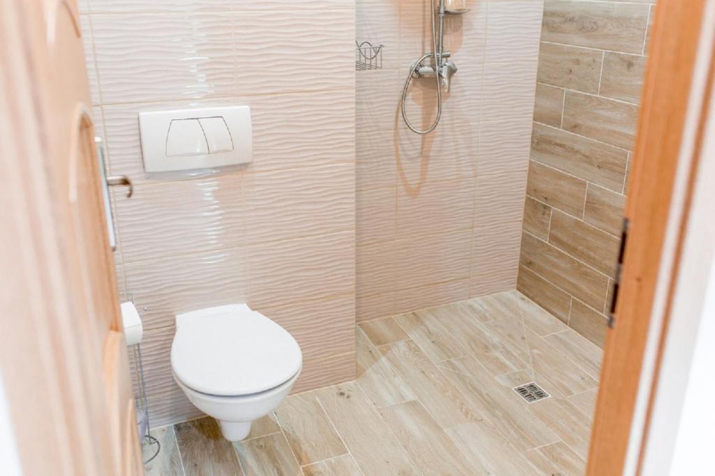 a small bathroom with a toilet and a shower at Apartament przy Kamiennej Chacie in Zalewo