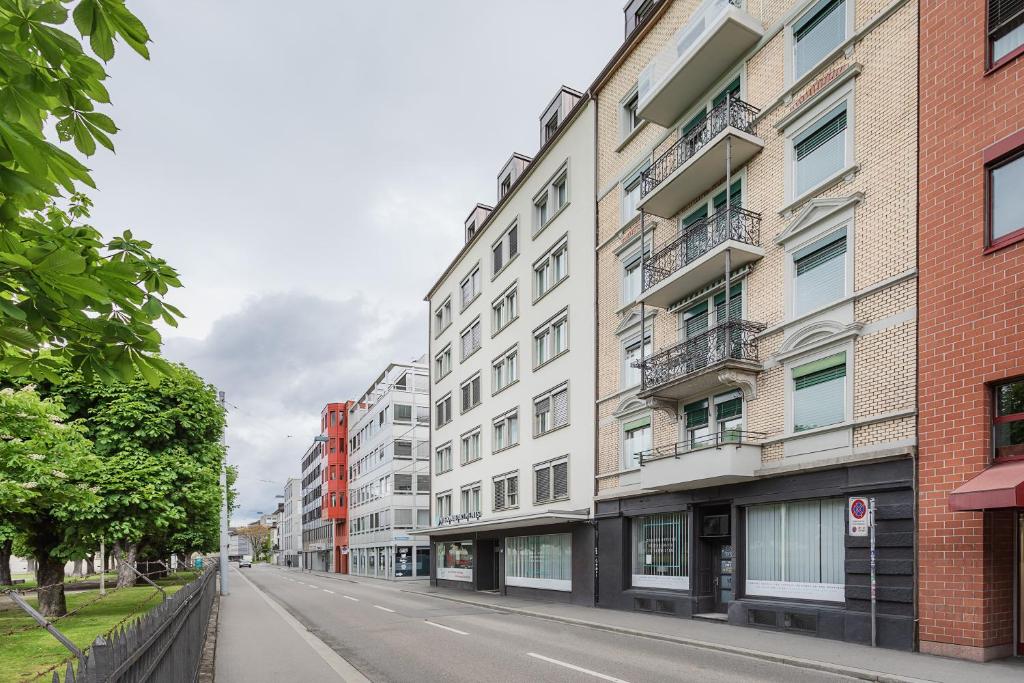 an empty street with tall buildings on a city street at VISIONAPARTMENTS Militärstrasse - contactless check-in in Zürich