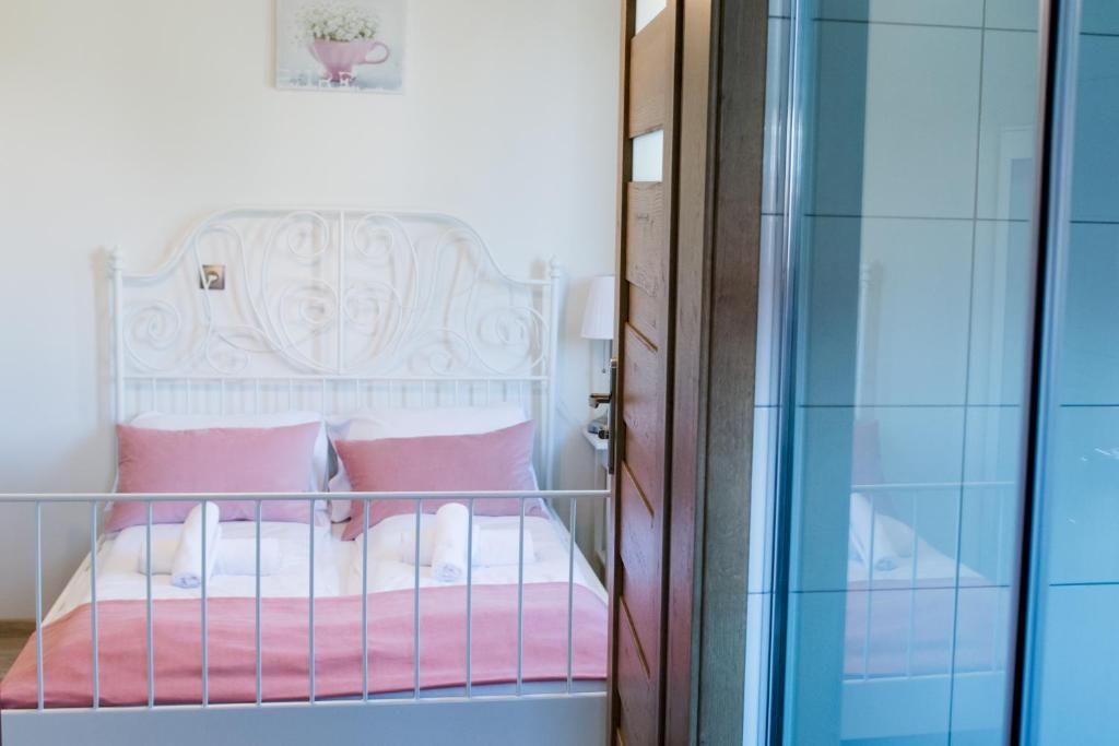 Harmony Hostel في زاتور: غرفة نوم مع سرير مع وسائد وردية وبيضاء