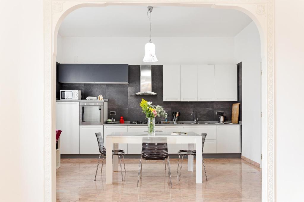 a white kitchen with a white table and chairs at Salvator Rosa Metro station Flat in Naples