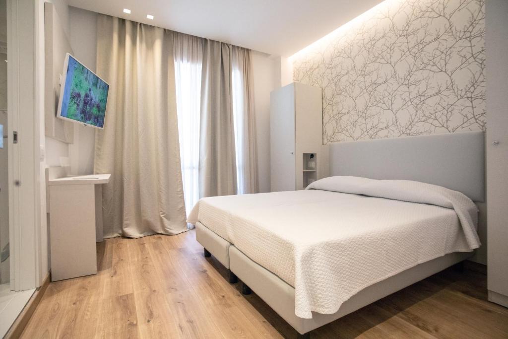 - une chambre avec un lit blanc et une grande fenêtre dans l'établissement Feel Good, à Rimini