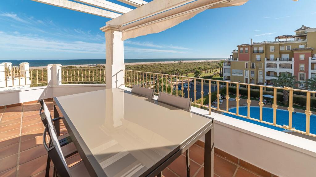 a balcony with a table and a view of the ocean at Apartamentos Costaluz Las Dunas in Isla Canela