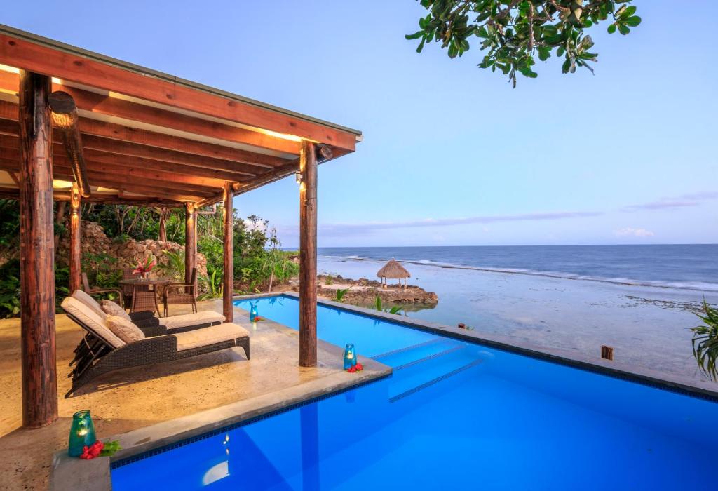 a house with a swimming pool next to the ocean at Savasi Island Resort in Savusavu