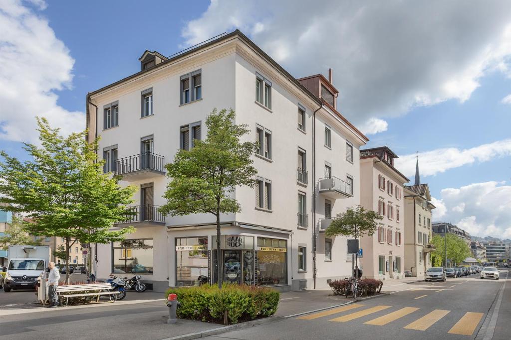 een groot wit gebouw aan een stadsstraat bij VISIONAPARTMENTS Zweierstrasse - contactless check-in in Zürich