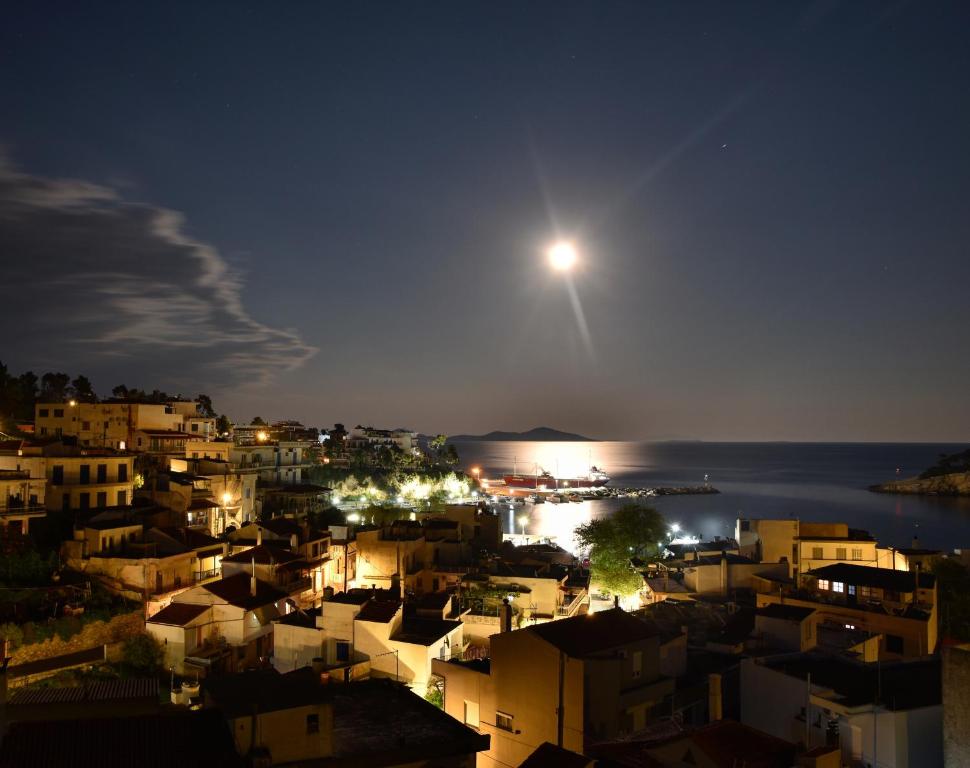 a view of a city at night with the moon at Angelos Design Suites in Patitiri