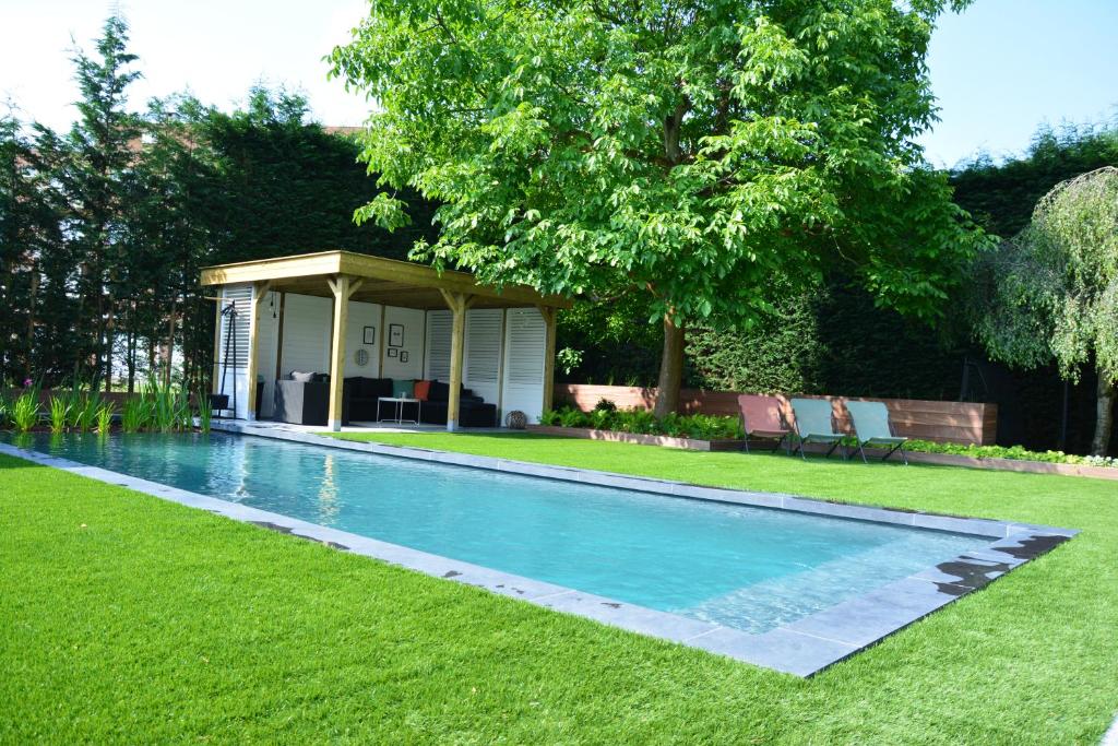 een zwembad in een tuin met een tuinhuisje bij B&B Maris Logies in Hasselt