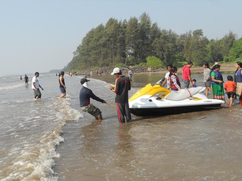 a group of people standing in the water near a boat at Ballaleshwar cottage in Alibaug