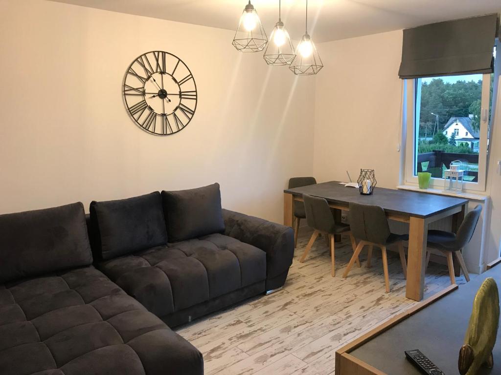a living room with a couch and a table and a clock at GOJA in Sztutowo