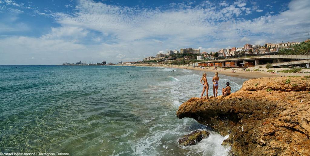 a group of people standing on the rocks at the beach at Tarragona Ciudad, El Serrallo AP-3 in Tarragona