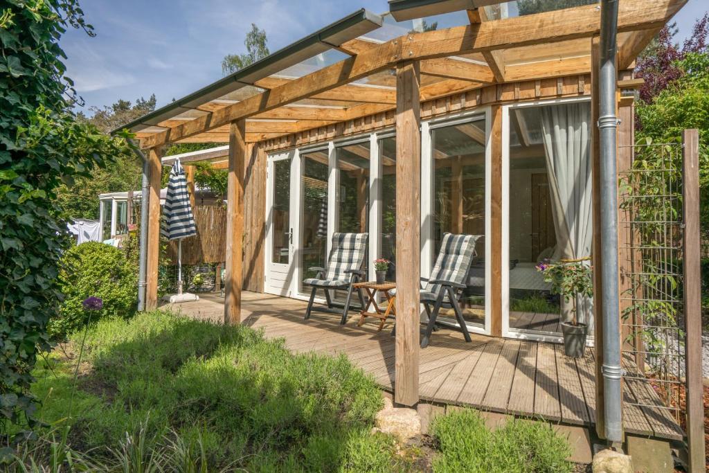 a wooden pergola with two chairs on a deck at B&Bveluwezoom in Eerbeek