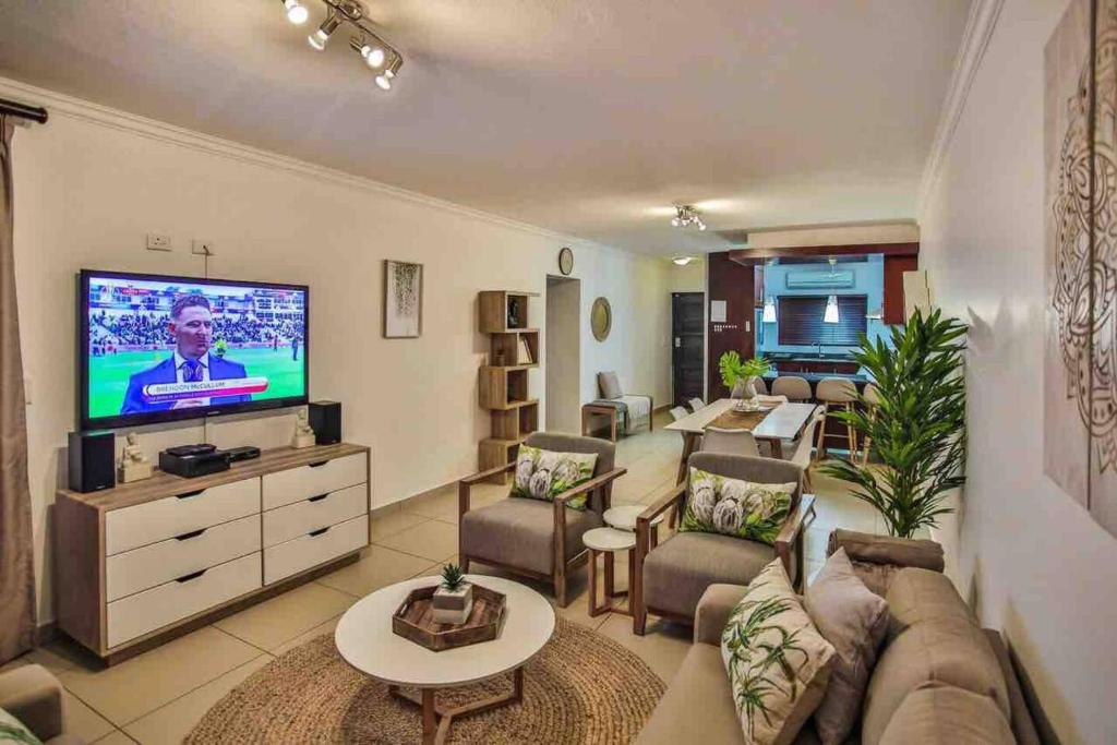 a living room with a couch and a flat screen tv at Komorebi Ballito in Ballito