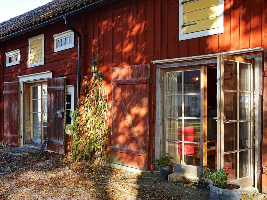 Une grange rouge avec une porte et des fenêtres. dans l'établissement Holiday home ÖDESHÖG, à Ödeshög