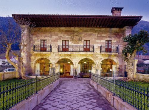 a large stone building with a fence in front of it at Hotel Palacio Guevara in Treceño