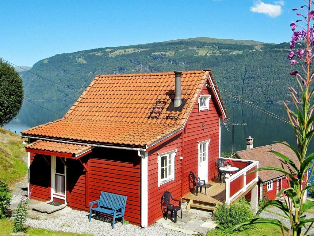 una casa roja con techo rojo y terraza en Two-Bedroom Holiday home in Utvik 1, en Sølberg