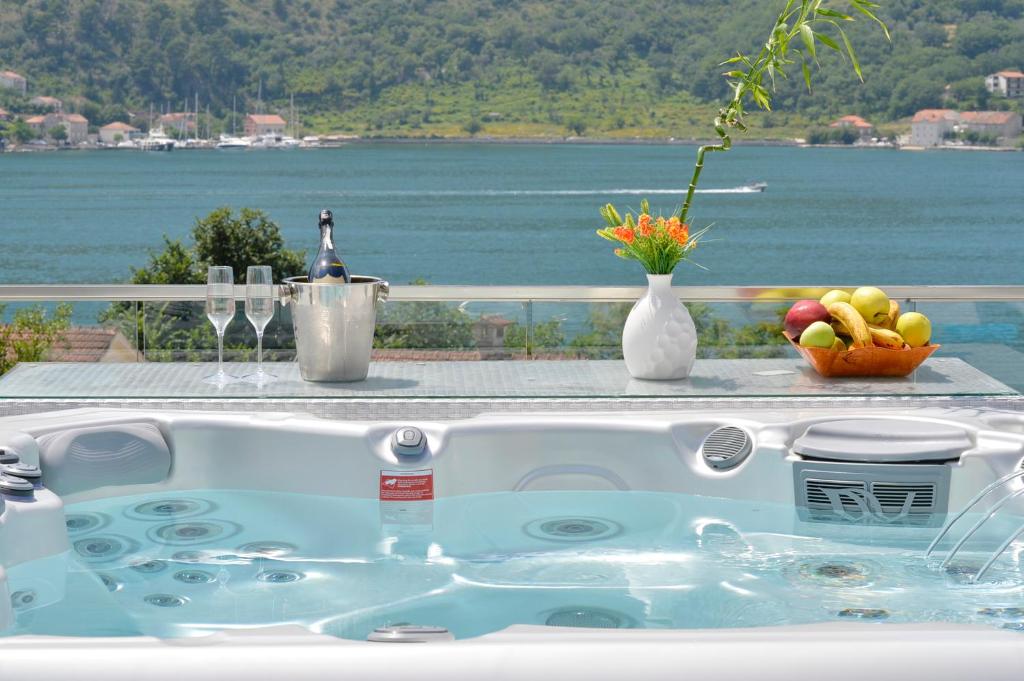 eine Badewanne mit einer Schale Obst und einer Flasche Wein in der Unterkunft Apartments Jovanovic - Alkima in Kotor