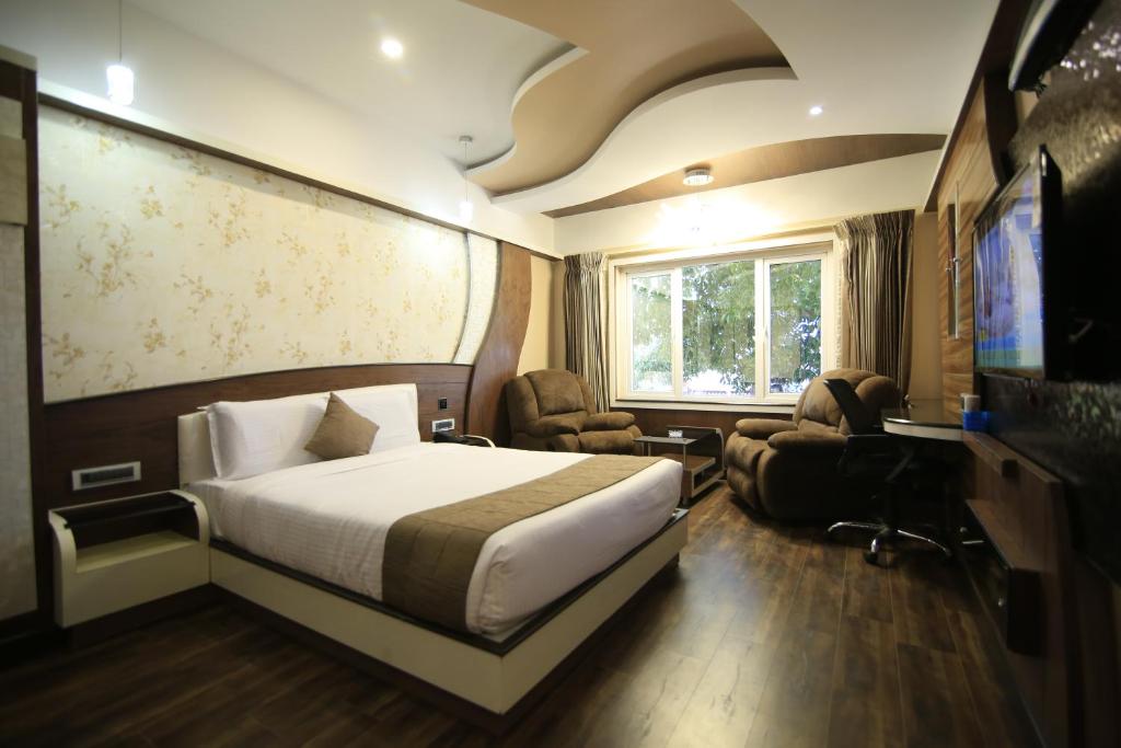 Habitación de hotel con cama y TV en Beverly villa, en Ooty