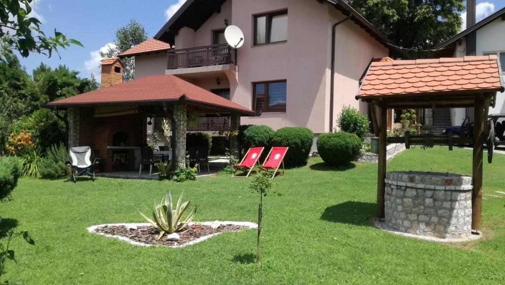 a house with two lawn chairs and a gazebo at Apartments Dedic in Dubrave Gornje