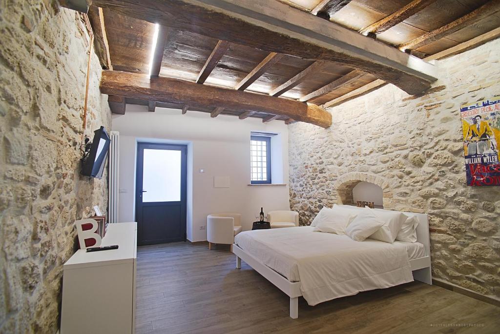 - une chambre avec un lit et un mur en pierre dans l'établissement La Ruetta in pieno centro storico, à Ascoli Piceno