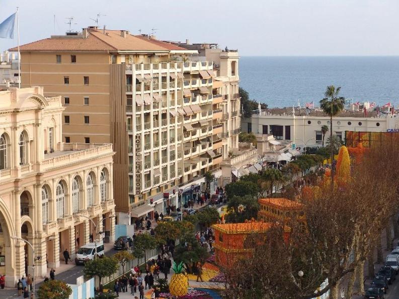 a city street with buildings and the ocean in the background at Hotel Chambord in Menton