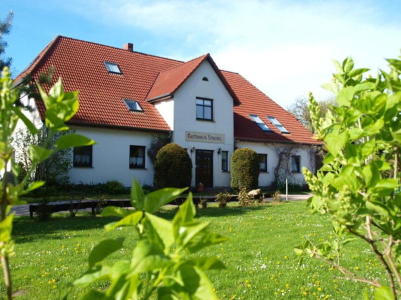 a white house with a red roof in a yard at Familienfreundlicher Landurlaub im Gutshaus in Trent