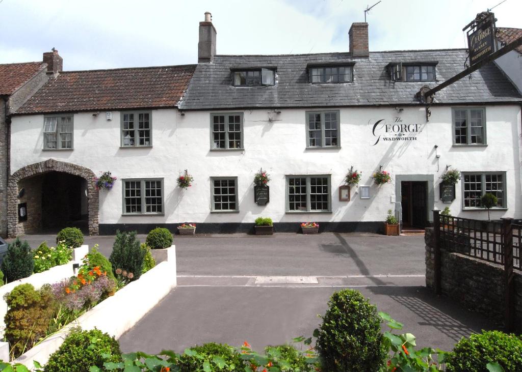 a white building with a courtyard in front of it at The George at Nunney in Frome