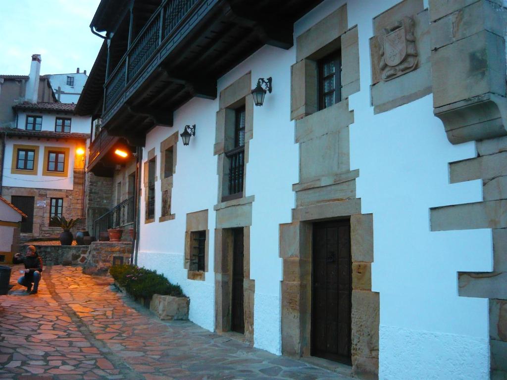 Bielva的住宿－Bielva Céntrico con Vistas，沿着一条鹅卵石街道走的女人,就在白色的建筑旁边